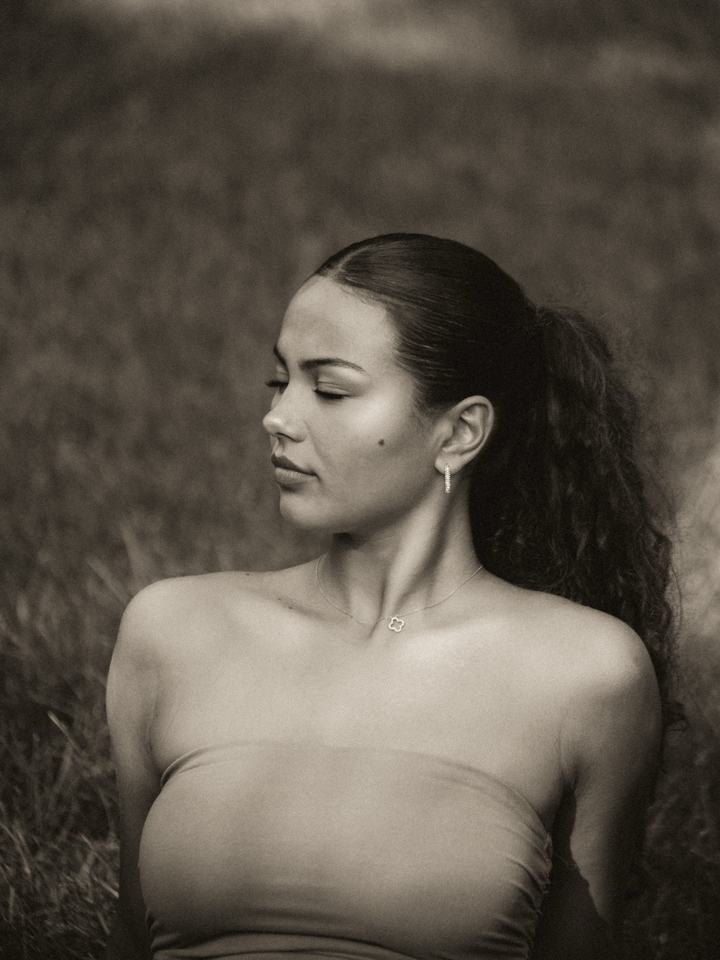 Black-and-white portrait, looking over her shoulder in a field