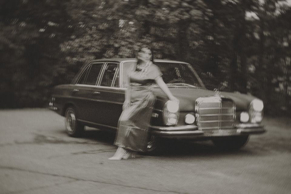 Esther leaning on a vintage Mercedes, black-and-white