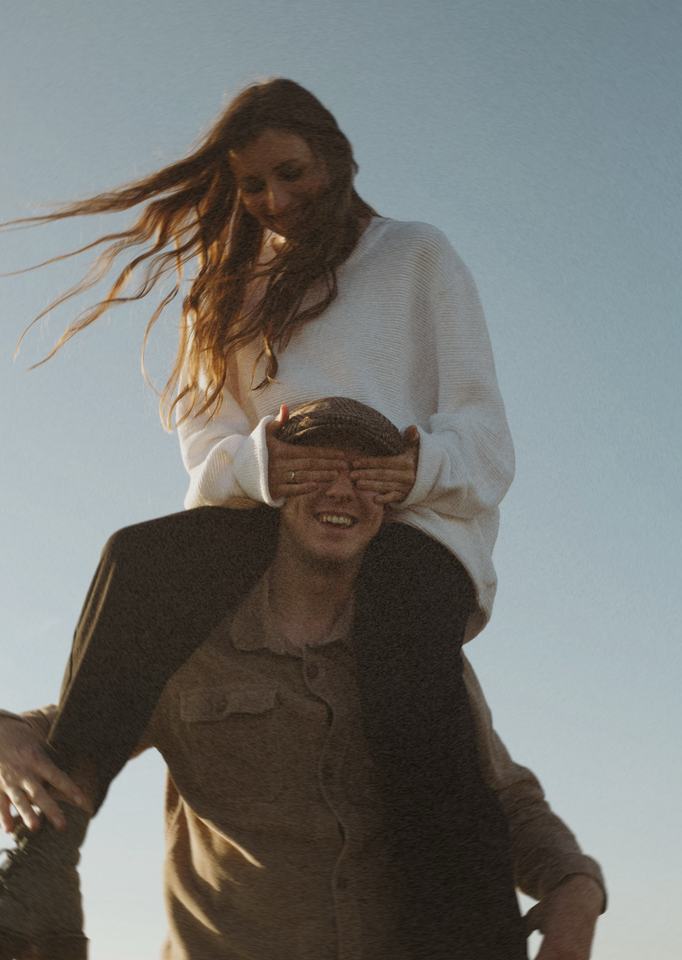 She covers his eyes from his shoulders, hair in the wind