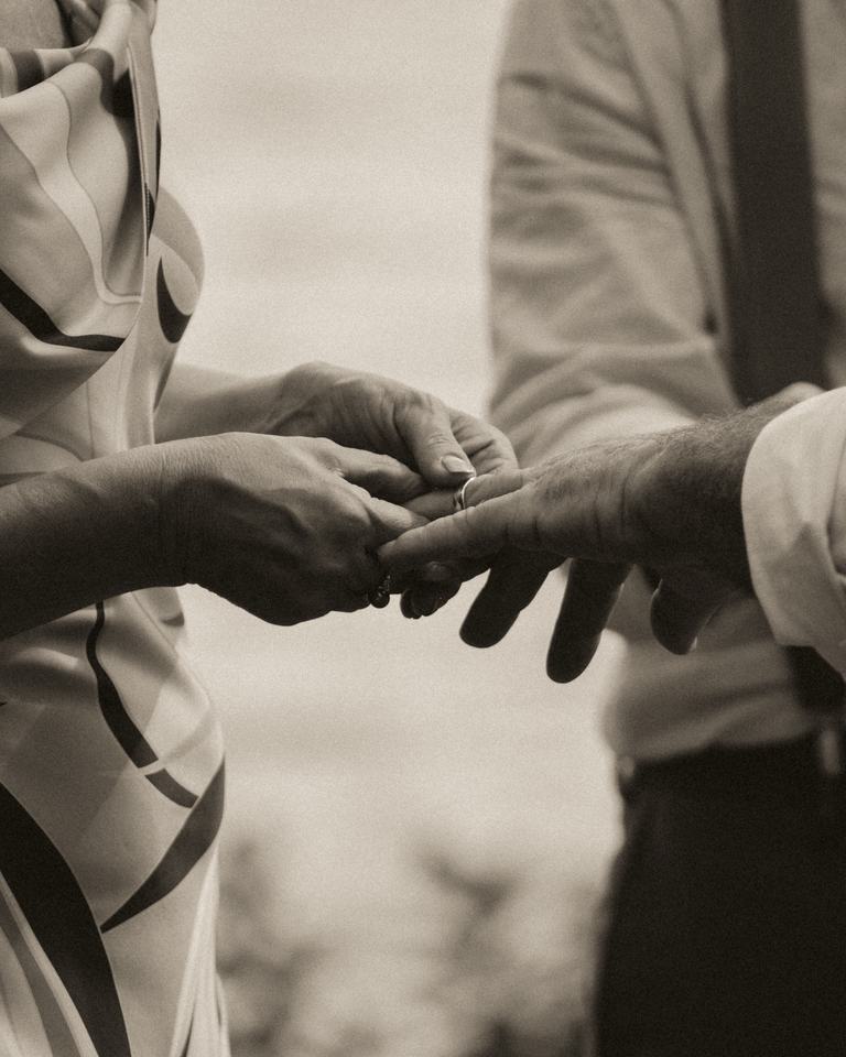 Black-and-white close-up of him slipping on her ring